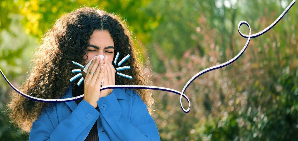Person sneezing into a tissue outdoors with curly hair and a blue outfit