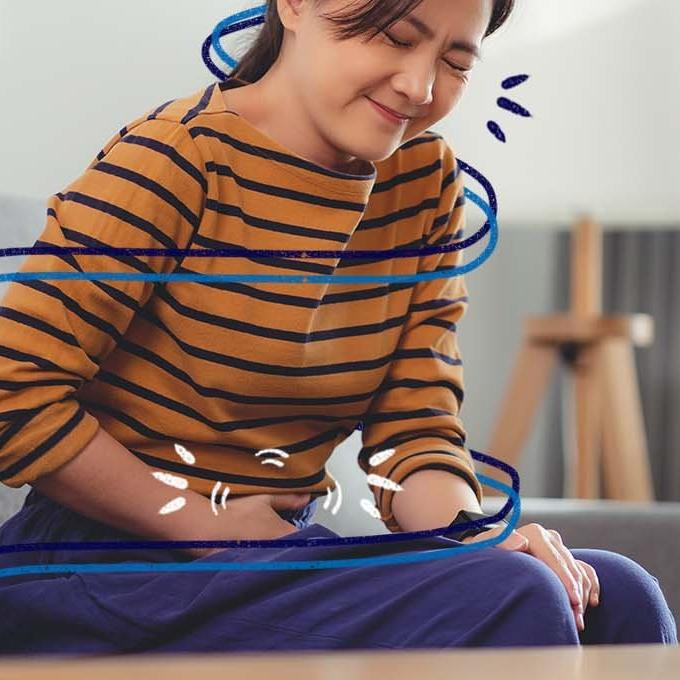 A person sat on a sofa holding their stomach in pain