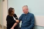 Two people smiling while using a blood pressure monitor