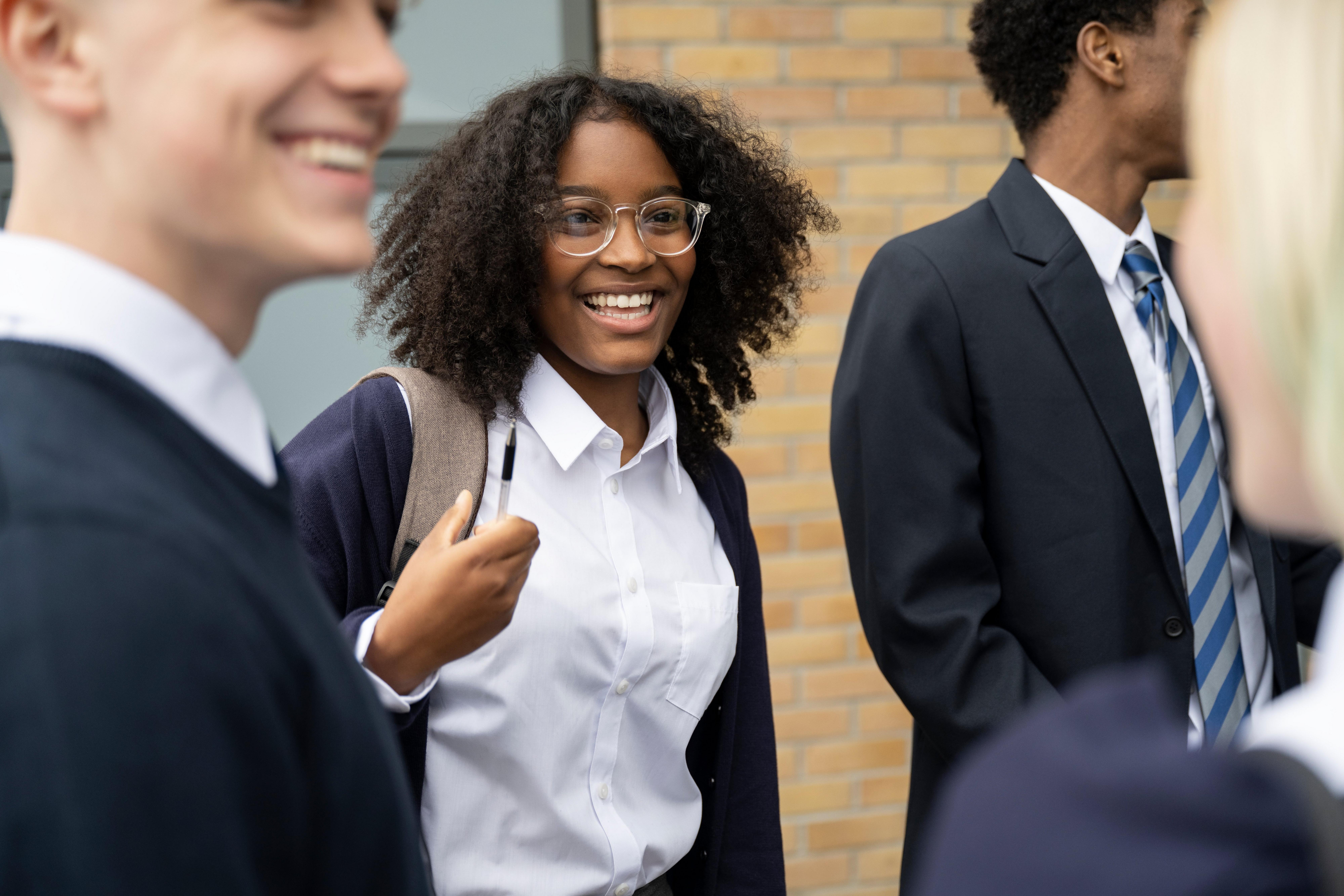 Students in school uniform standing and chatting in a school corridor.