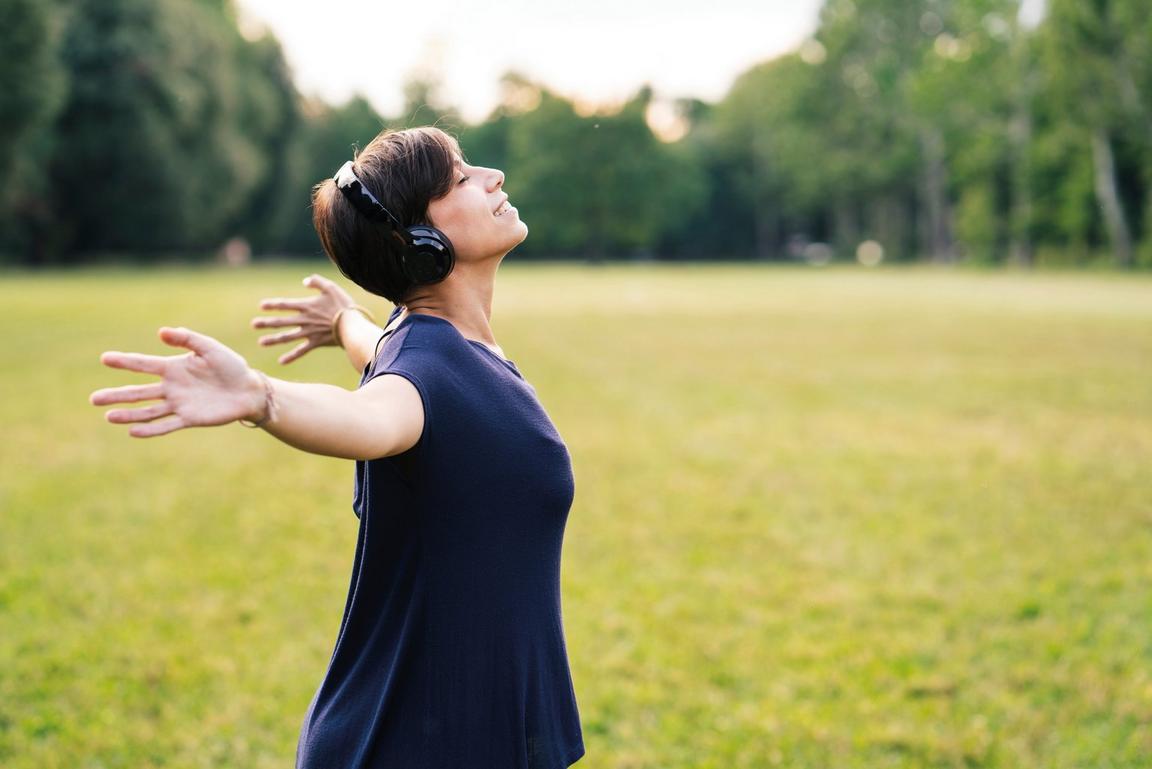A smiling person running outside wearing headphones