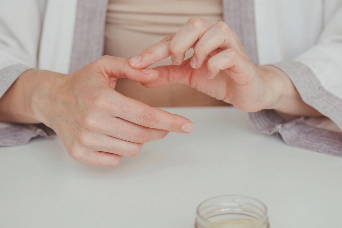 Hands massaging a finger against a white background
