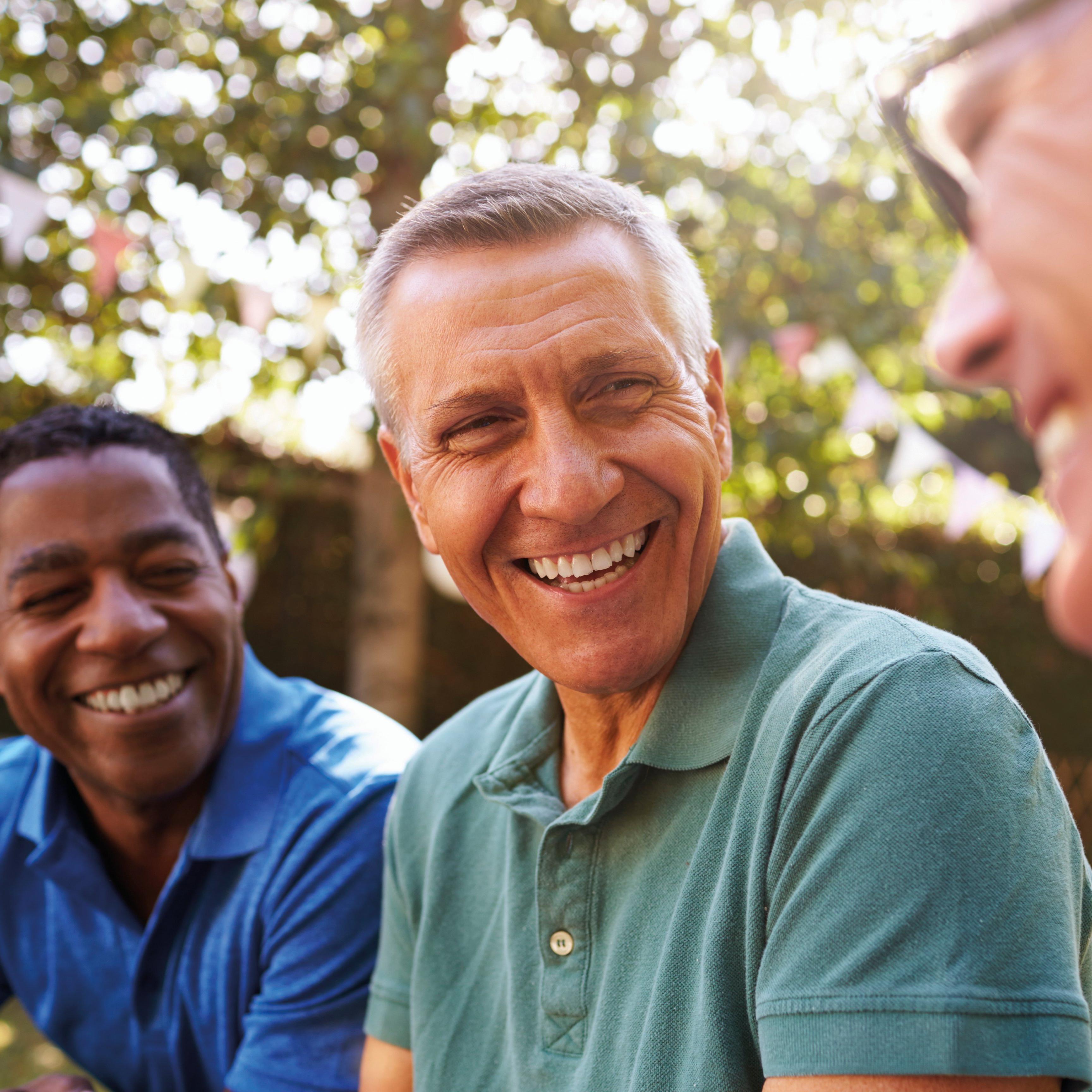 Three men sat outside smiling