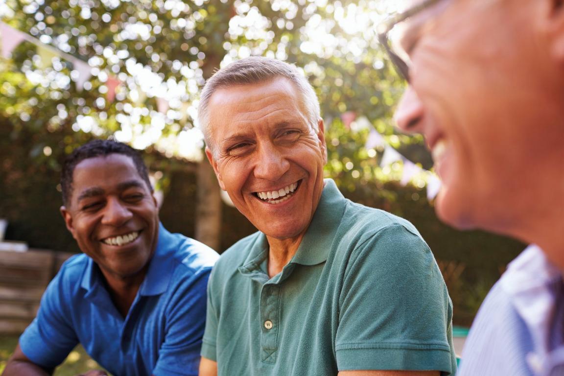 Three men sat outside smiling