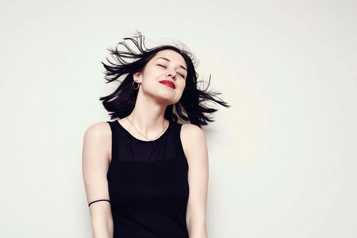 A woman with dark hair smiling with her eyes closed
