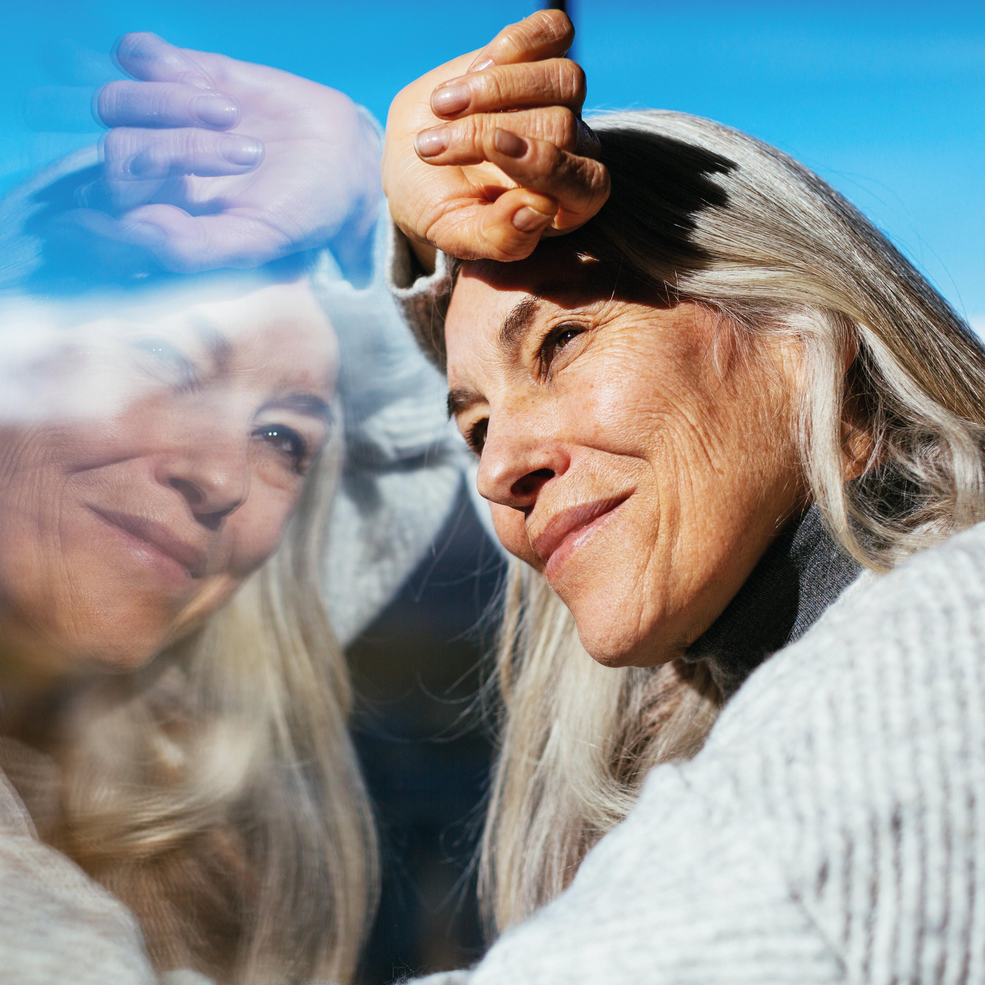 A woman looking out of a window against her reflection
