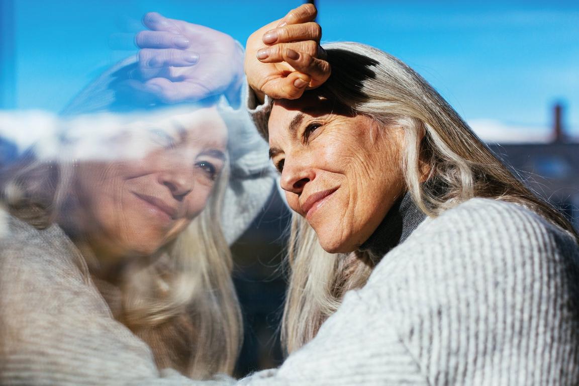 A woman looking out of a window against her reflection