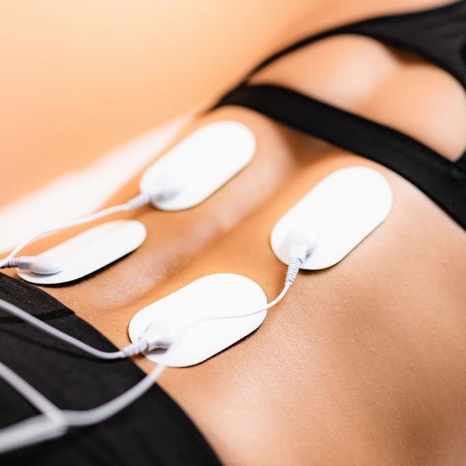 Someone lying down with a TENS machine on their back