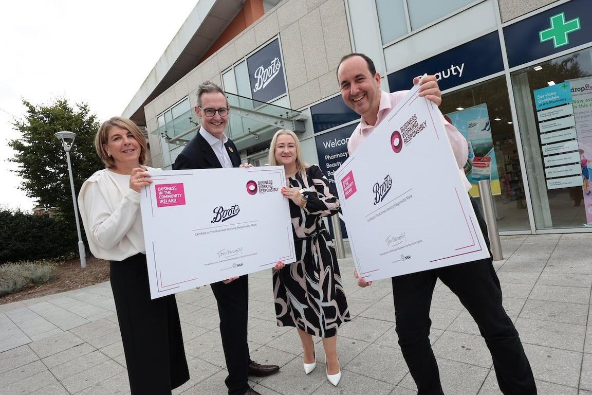 Four people holding certificates outside a Boots store.