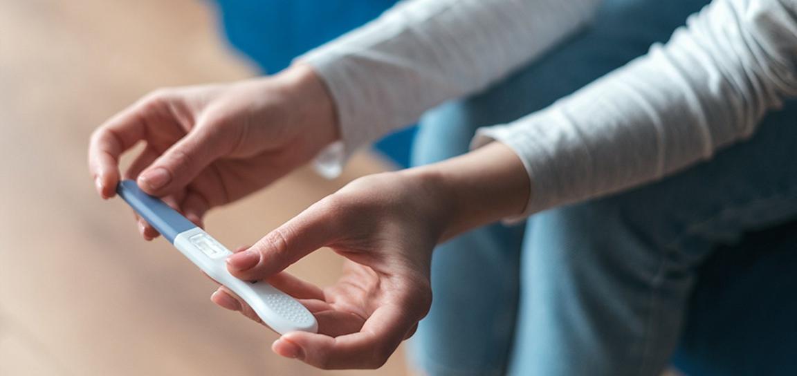 Close-up of hands holding a pregnancy test.