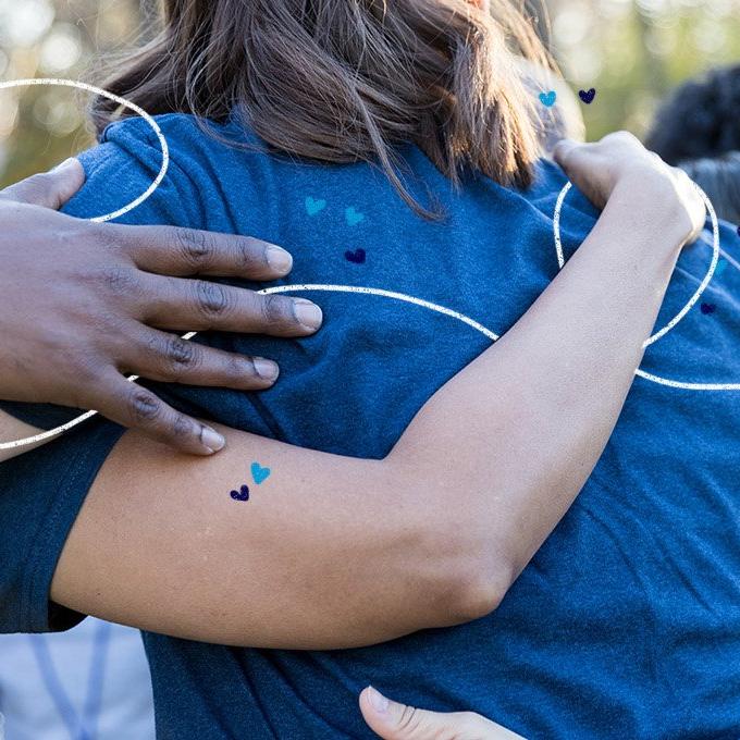 A group of people stood together with their arms around each other