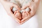 A man and a woman kissing a babies feet with a small child next to them