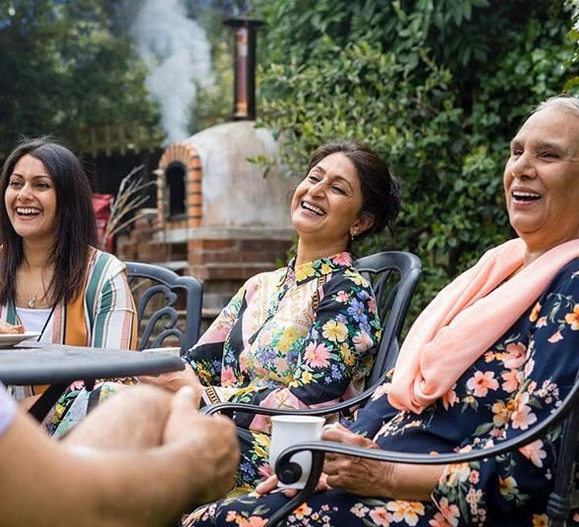Three people laughing sat round a table