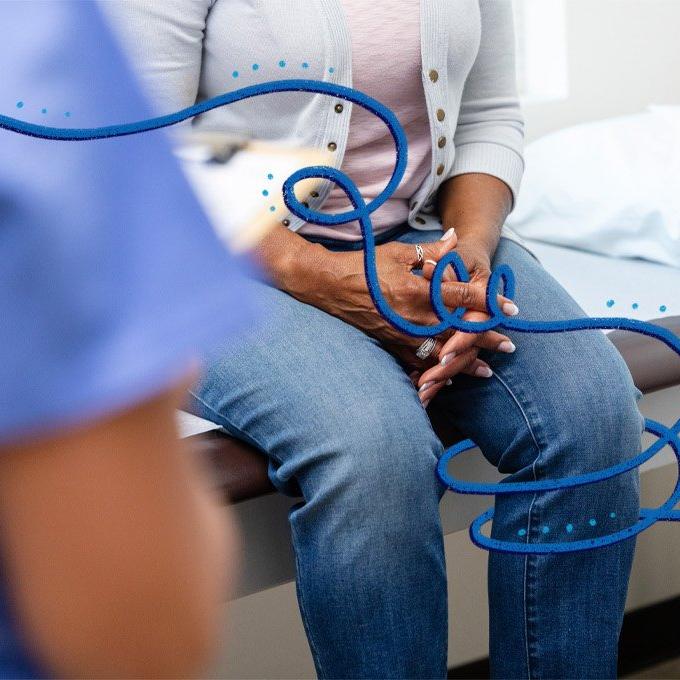 Person sitting on a medical exam table with hands clasped, decorated with blue swirling lines