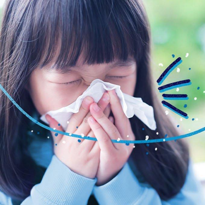 Someone sneezing into a tissue outside