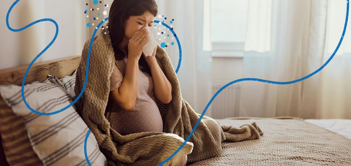 A pregnant woman sat sneezing on a bed