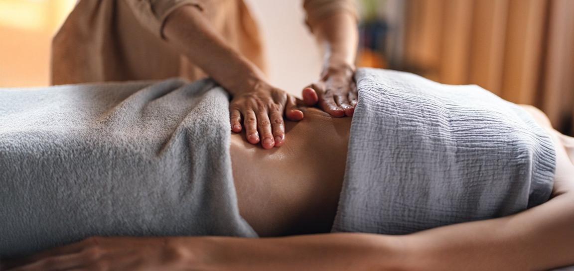 Close-up of a massage with hands applying pressure on a covered torso.