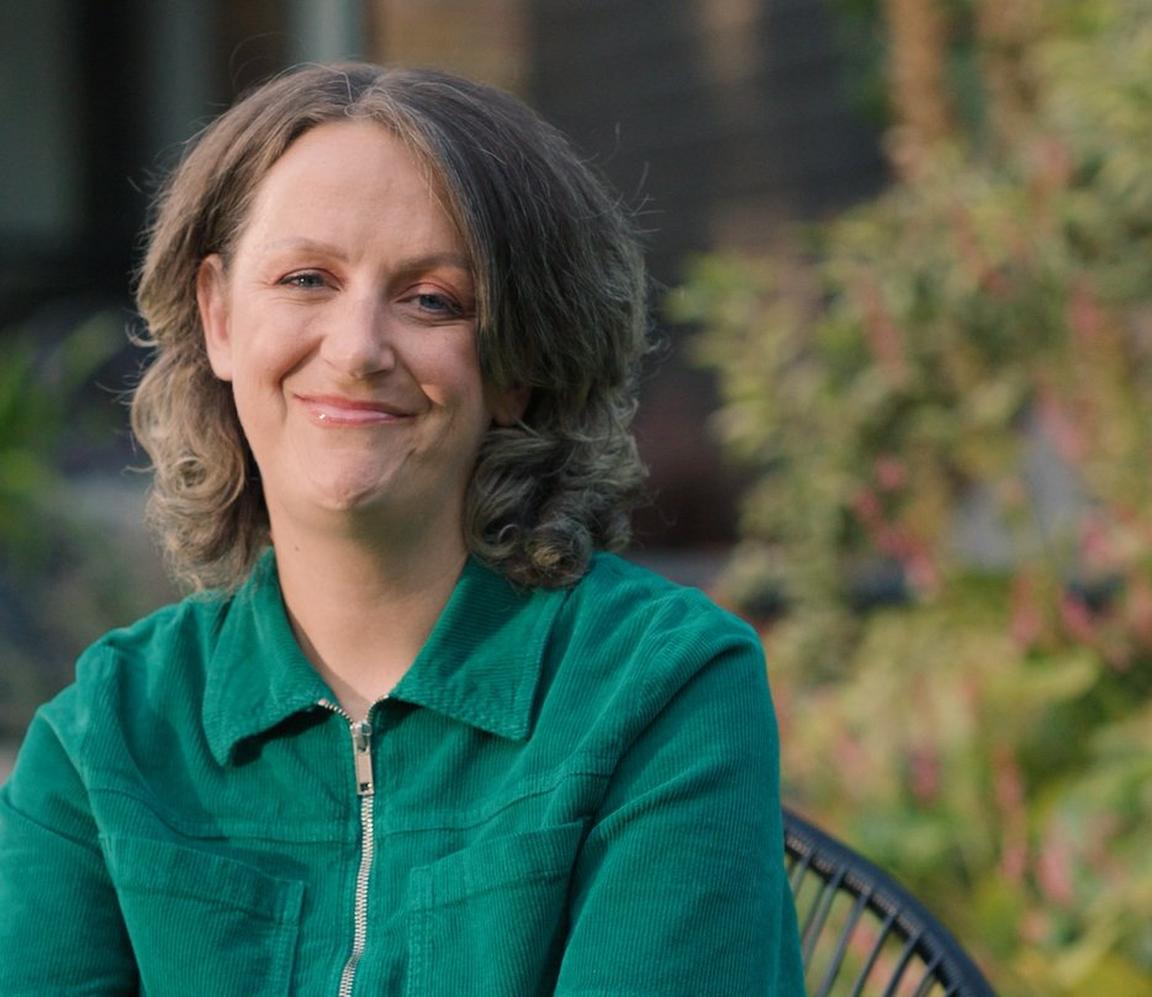 A woman wearing a green shirt smiling