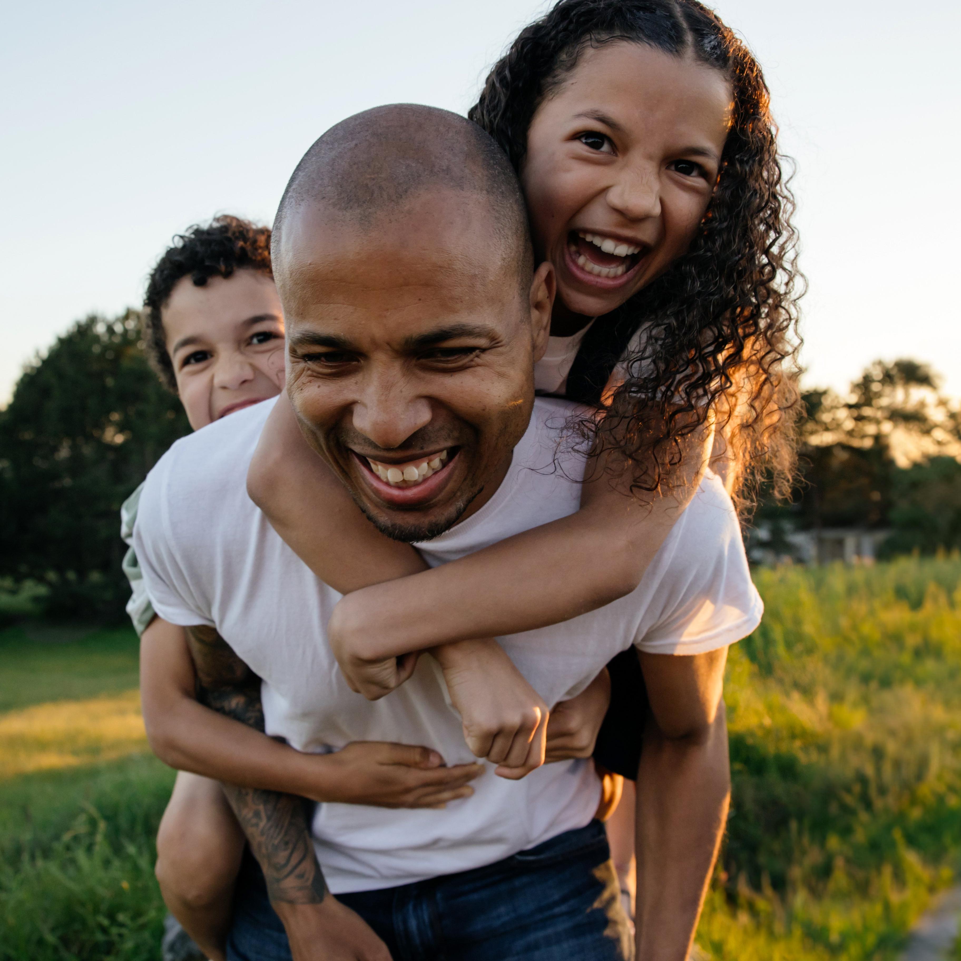 A man giving two children a piggyback ride