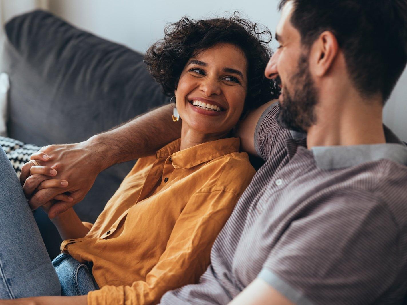 A man sitting with a women on a sofa with his arm around her shoulder