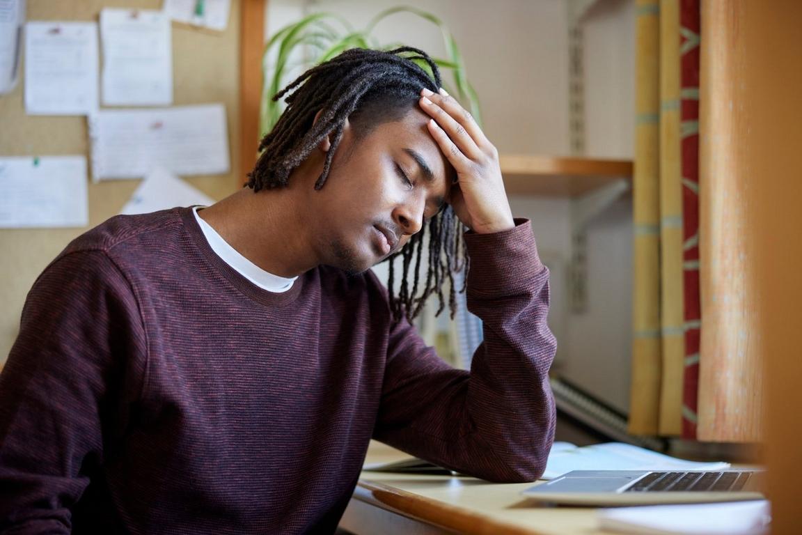 Someone holding their hand against their head while sitting at a desk