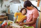 A woman and child in a kitchen, preparing food together with fruits and vegetables on the table