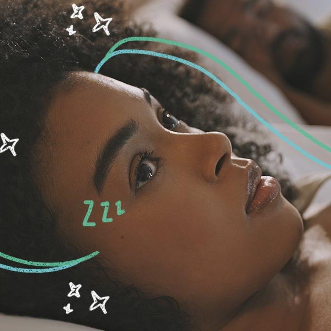 A person sleeping in a bed with someone lying awake next to them surrounded by stars