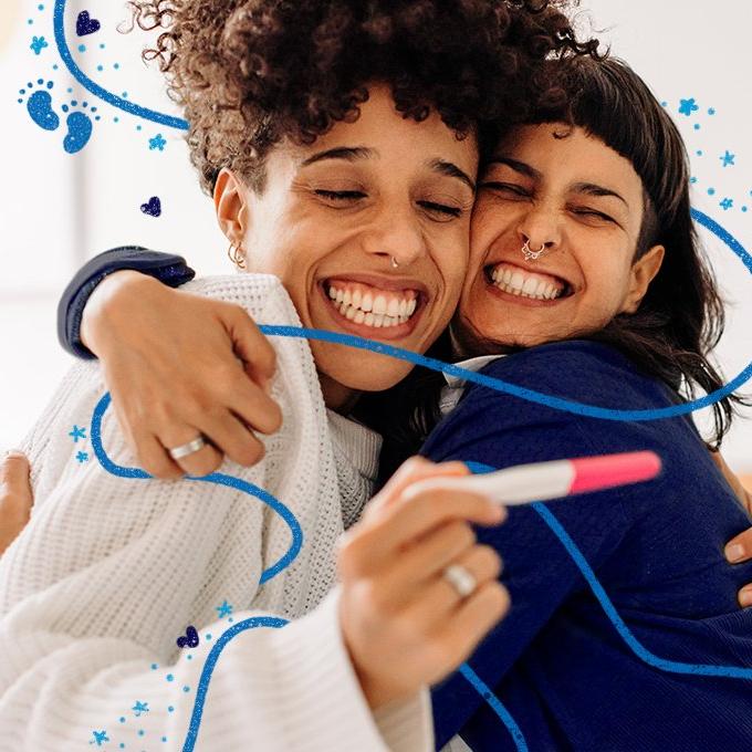 two people embracing and smiling looking at a pregnanacy tester pen