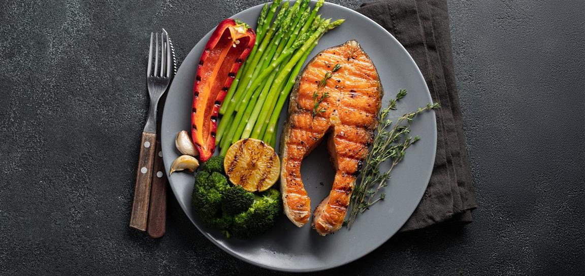 Slices of pickle besides a salmon fillet on a wooden platter