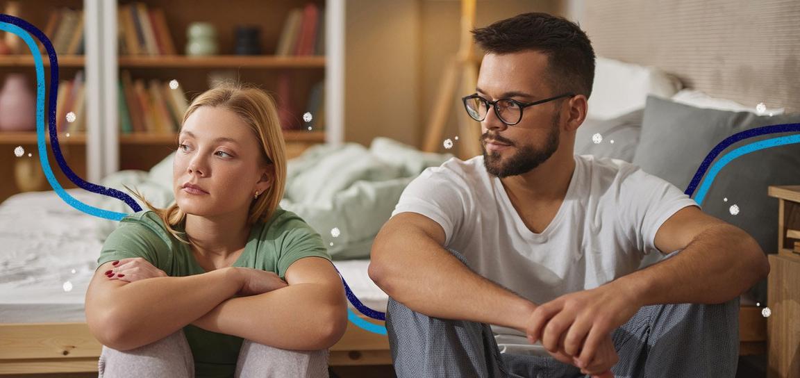2 adults sat on the floor next to each other in a bedroom