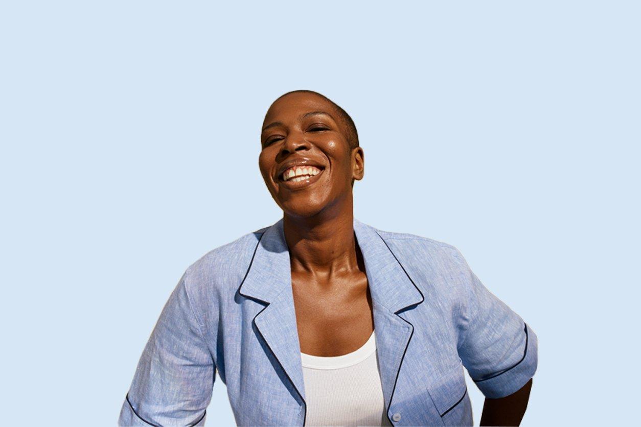 Smiling woman in a light blue blazer against a vivid blue background.