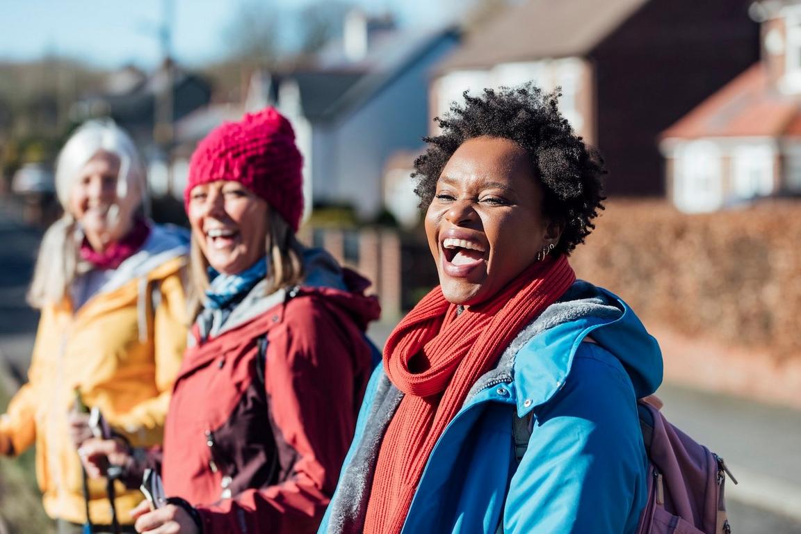 Two women laughing outdoors in casual winter clothing.