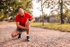 Person kneeling on a gravel path, holding their knee, with trees in the background