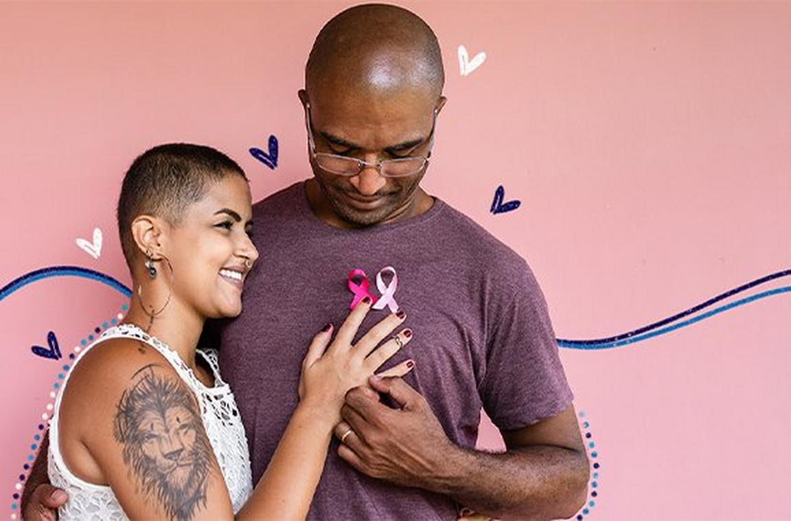 Two people hugging wearing a cancer trust badge