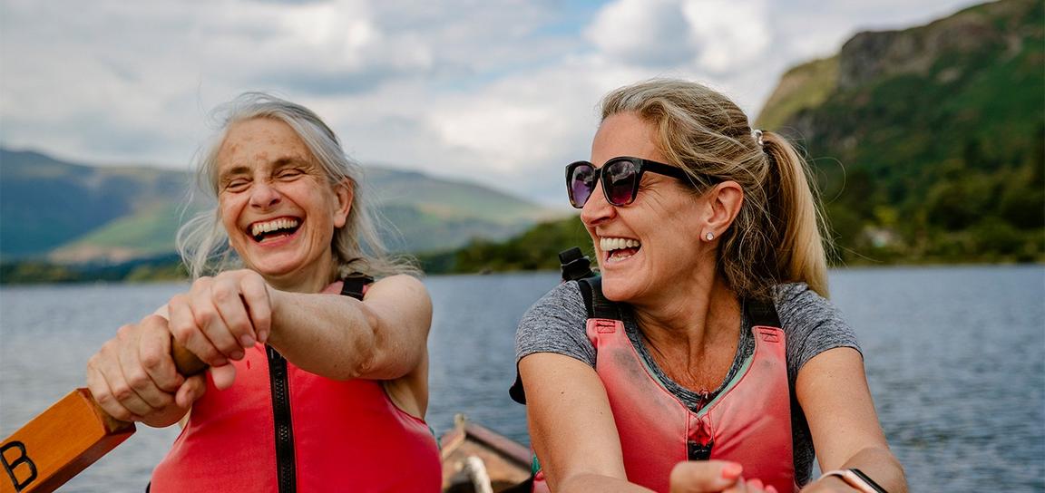 Two people smiling wearing red jackets rowing.