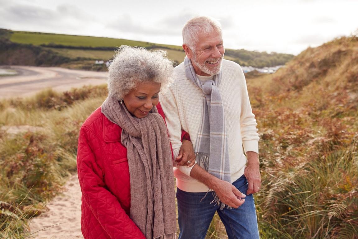 Two elderly people holding each others arms on a walk outside