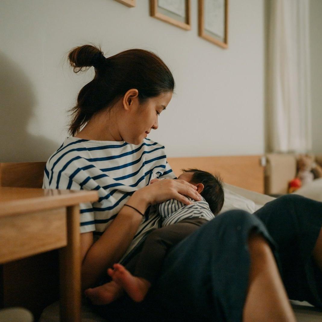 Woman breast feeding her baby. they are both wearing striped clothing