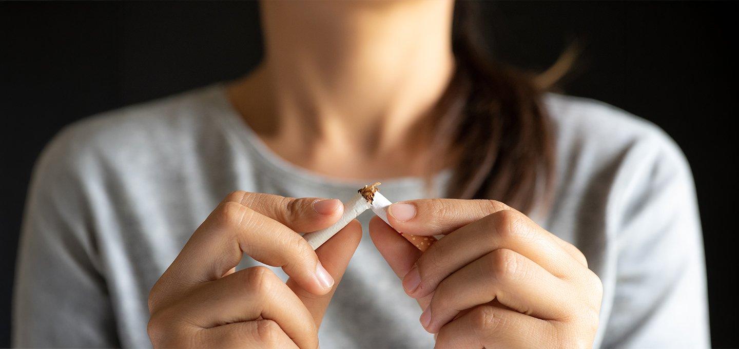 Person breaking a cigarette in half with both hands.