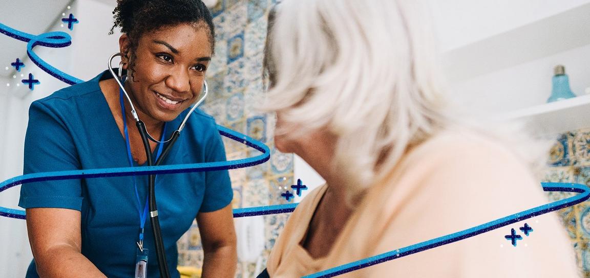A female nurse wearing a stethoscope smiles at an aldery patient