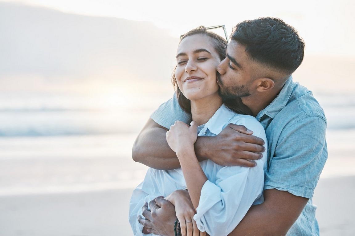 Two people standing side by side, holding hands with one arm resting on the other’s forearm.