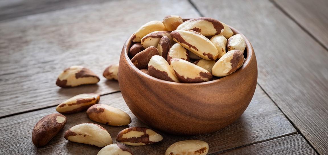 A rustic wooden bowl brimming with Brazil nuts, emphasizing their earthy tones and distinctive, rough shells.