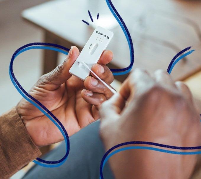 Person holding a COVID-19 antigen test cassette with a swab