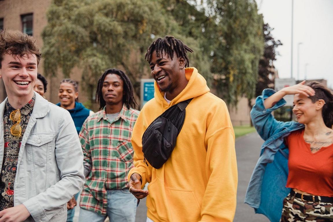 A group of young adults walking outdoors, with one wearing a yellow hoodie