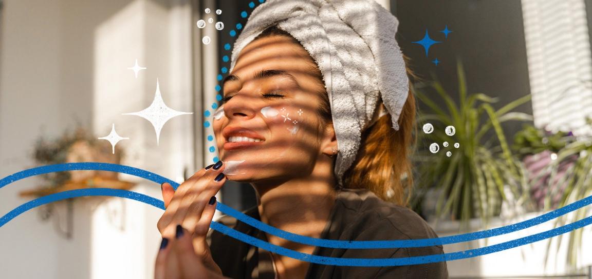 A person with a towel on their head applies cream to their face in sunlight, surrounded by decorative sparkles and bubbles