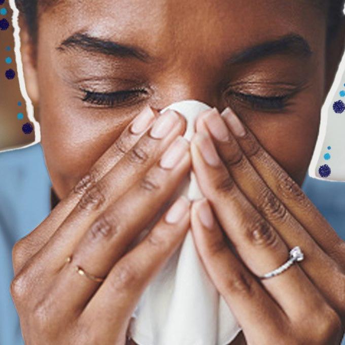A person sneezing into a tissue with blue dots around them.