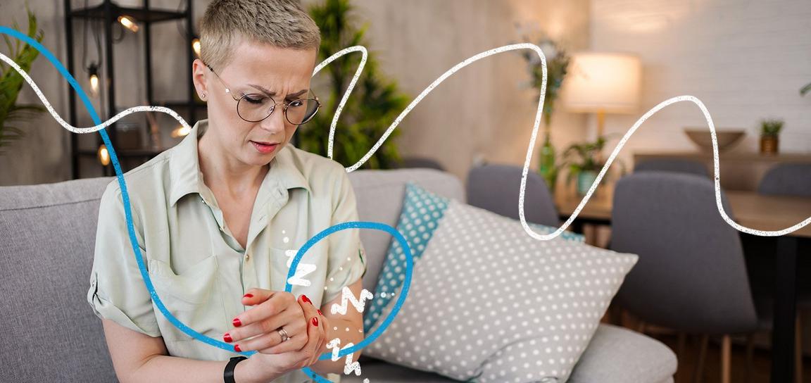 A woman with glasses holding her wrist in pain