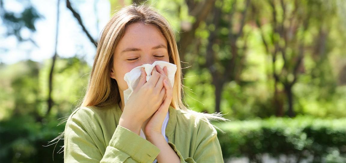 A person stood outside blowing their nose into a tissue