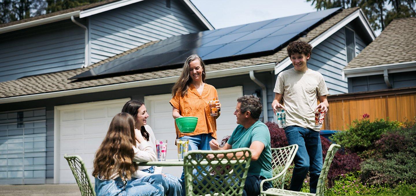 Five people socialising outdoors in front of a house with solar panels.