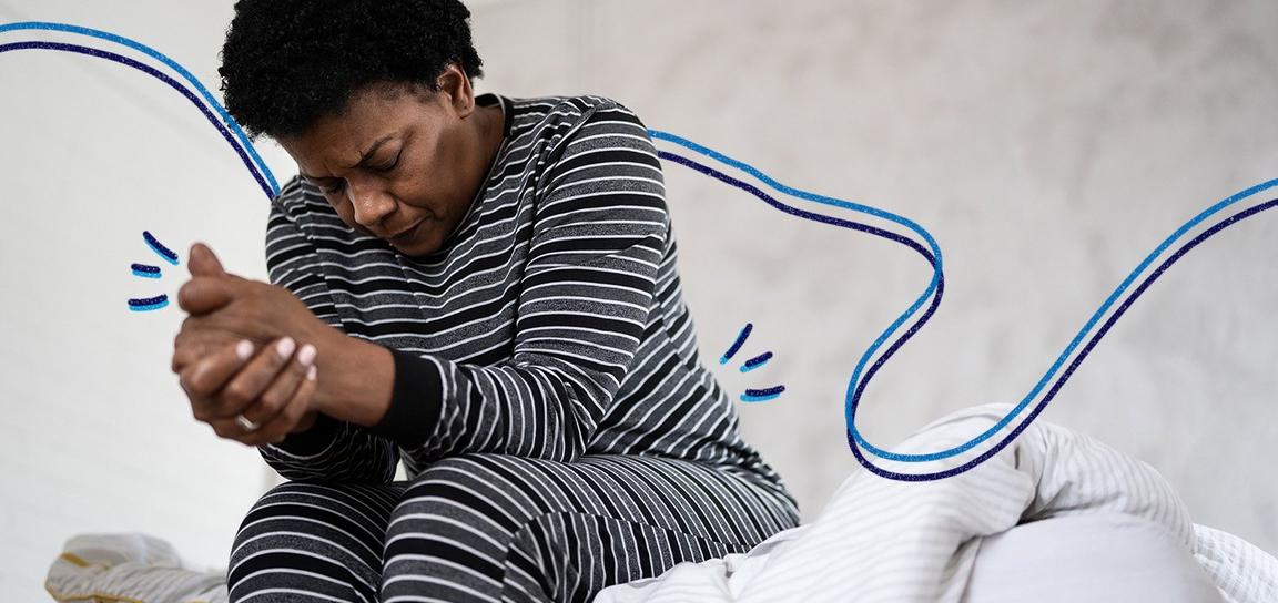 A person sat on the side of the bed in pyjamas looking in distress