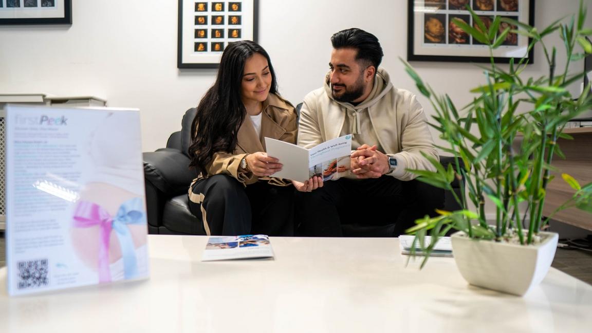 A man and woman sitting on a sofa looking at a document together.